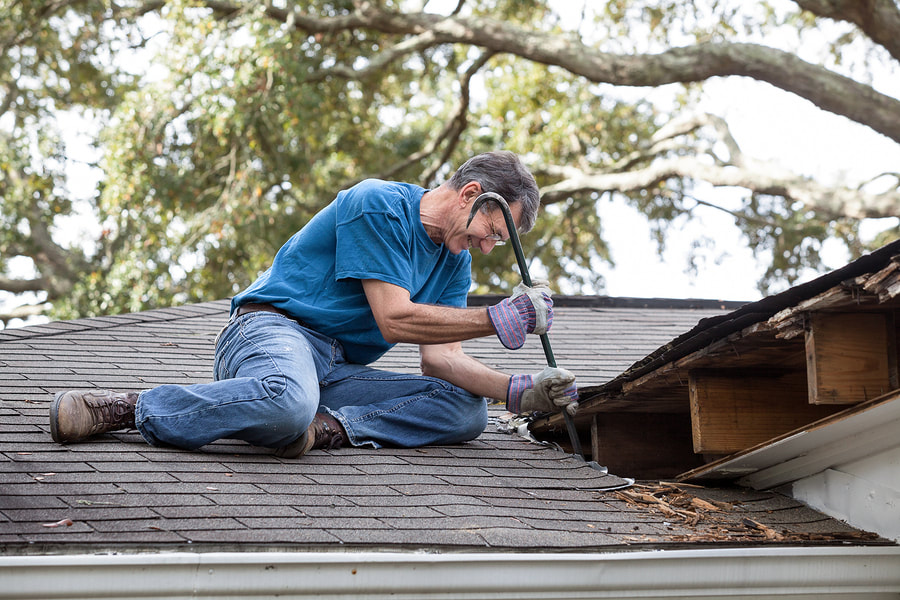 man removing roof shingles